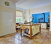 Free-standing counter, modern barstools and AGA cooker in blue-painted niche in open-plan kitchen