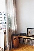 Vintage wooden speakers, record collection below sideboard in corner and glass display case of toy cars on windowsill behind curtain