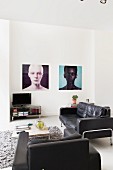 Black leather sofa and armchair around coffee table and large portraits on wall in minimalist interior