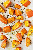 Diced pumpkin with thyme on a piece of baking paper