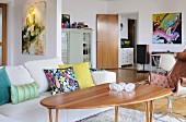 Sofa with scatter cushions, wooden table and leather armchair in open-plan interior