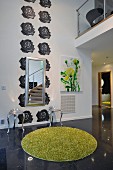 Floral wall motifs in an open-plan living room with a post-modern stool, a mirror and a green, thick-pile rug in the foreground