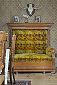 Jagdtrophäe über majestätisch klassizistischem Sessel mit floralem Samtpolster; vorne Stuhllehnen eines traditioneller Essplatzes