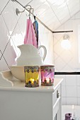 Orientalisch verzierte Windlichter und Waschschüssel mit Wasserkrug auf Landhauskommode in weißem Badezimmer mit romantischem nostalgischem Flair