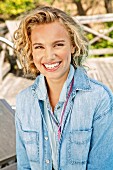 A young blonde woman outside wearing a denim shirt