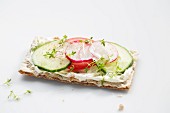A crispbread topped with cucumber, tomato, radishes and cress