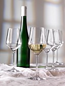 Weissweinglas, Weinflasche und leere Gläser