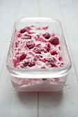 A tub of frozen raspberry yoghurt (close-up)