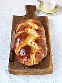 A plaited yeast dough loaf with raisins on a chopping board