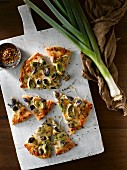 Pizza slices with red sauce, mozzarella, leeks purple Brussels sprouts and thyme