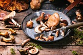 Fresh forest mushrooms in an old pan with a fork on a wooden table