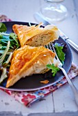 A halved puff pastry parcel with a cheese filling on a rocket salad