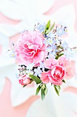 Vase mit Blumenstrauss aus rosa Nelken und Vergissmeinicht (Draufsicht)