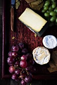 Various types of cheese and grapes on a wooden surface
