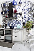 White kitchen counter against wall tiled with traditional, white and blue, country-house-style tiles