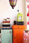 Oriental glass lantern above jumble of books on top of flea-market cabinets