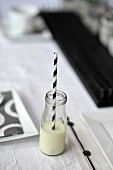 A mini bottle of vanilla milk with a black-and-white stripped straw