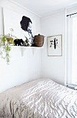 Bed with shiny bedspread below picture and house plant on bracket shelf