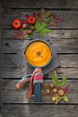 Pumpkin soup in a saucepan on a wooden surface with autumnal decorations