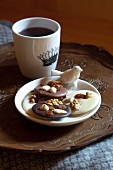 Plate of biscuits with china bird and mug of coffee on vintage tray