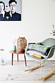 Classic rocking chair and lantern on table below picture on wall