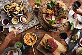 Various party dishes (chips, dips, soufflé, beef) and red wine