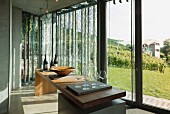 Wine glasses on a large wooden table in front of floor-to-ceiling windows in a vinotheque; Weingut am Stein, Würzburg
