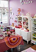 Shop with lilac-painted walls and ornaments on table in front of shabby-chic cabinet