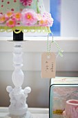 Price tag hanging from table lamp with white ceramic base and decorated lampshade