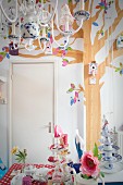 Multi-armed chandelier above table decorated with romantic charm; nesting boxes hung on wall with tree mural