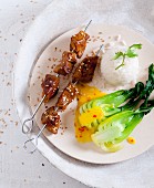 Seitan and sesame seeds skewers with bok choy, orange and chilli sauce and scented rice