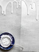 A view of icing sugar in a sieve on the plates with liquid icing sugar running down from the top of the picture
