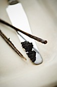 Vanilla seeds on a knife with the scraped-out vanilla pod