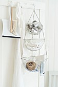 Dustpan and brush and tiered baskets suspended from peg on door in white kitchen