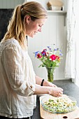 Woman baking rhubarb cake next to window in kitchen