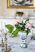 Silver candlesticks and posy in white and blue vase on table