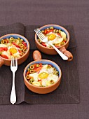 Baked eggs with potatoes, peppers, onions, olives and tomatoes