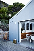 View from wooden deck with garden shower into open-plan kitchen with dining area