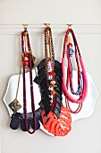 Various necklaces hung from hooks on white picture rail