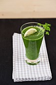 A green smoothie garnished with parsley and lemon