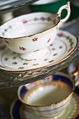 Antique gold-rimmed teacups with floral patterns and matching saucers