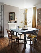 Wood and metal chairs around wooden table with turned legs painted pale grey in traditional dining room