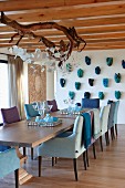 Speisesaal mit bequemen Sesseln und Ast-Leuchte; Masken an der Wand, Sessel und Accessoires in Blautönen