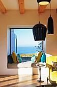 Mattress and scatter cushions in niche of panoramic window with sea view
