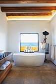 Free-standing bathtub below window with sea view in designer bathroom