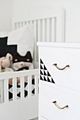 White chest of drawers with brass handles and geometric pattern