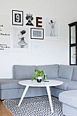White, retro side table on black and white patterned rug in front of grey corner sofa