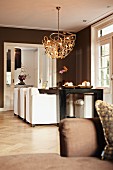 Modern pendant lamp above dining table and white upholstered chairs in brown-painted interior with traditional ambiance