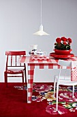 Rot-weisser Mustermix mit kariertem Tisch und farbig lackierten Stühlen auf Blumenteppich