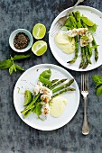 Fish skewers on a bed of green asparagus with a lime sauce
